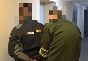Nieumundurowany policjant zakłada kajdanki na ręce zatrzymanego mężczyzny