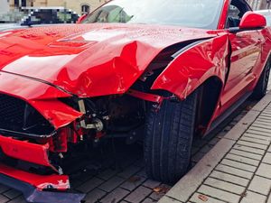 Uszkodzony czerwony  pojazd po zdarzeniu drogowym