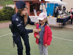 Umundurowana policjantka przypina dziewczynce odblask na bluzie