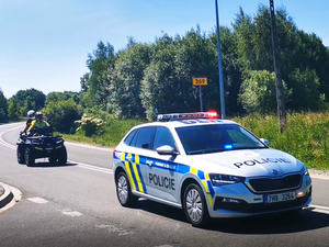 oznakowany czeski radiowóz poruszający się po asfaltowej drodze, za nim quad