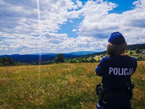 Umundurowana policjantka stojąca na łące, w tle górski krajobraz