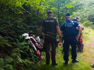 Leżący w lesie cross oraz dwóch funkcjonariuszy ze Straży Leśnej i Policji