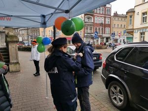 Policjantka przypina wstążkę na kurtkę mężczyzny