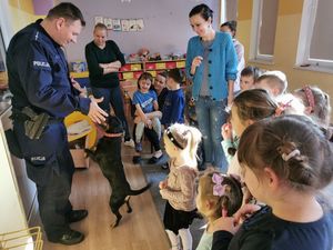 Policjant z psem służbowym i wokół niego grupa dzieci