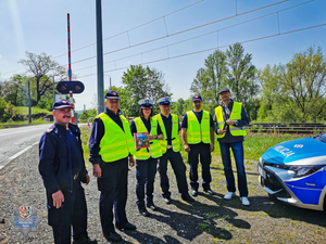 Zdjęcie grupowe przy przejeździe kolejowym funkcjonariuszy policji, straży ochrony kolei i koordynatora akcji &amp;quot;bezpieczny przejazd&amp;quot;, którzy stoją przy przejeździe kolejowym