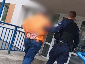 Mężczyzna w kajdankach prowadzony przez policjanta