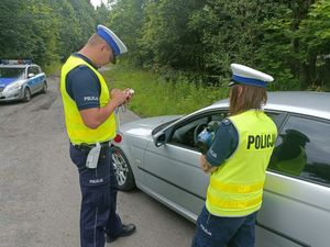 Dwóch funkcjonariuszy Wydziału Ruchu Drogowego podczas kontroli drogowej. Sprawdzania uprawnień kierującego