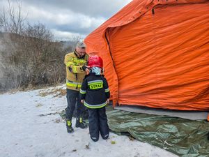 strażak ubiera dziecku hełm strażacki