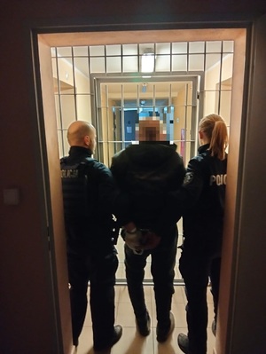 dwóch funkcjonariusz trzyma zatrzymanego mężczynę